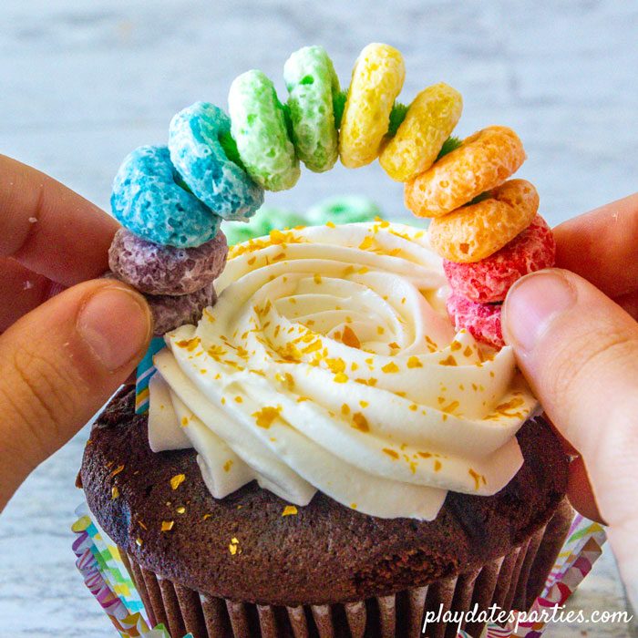 Making rainbow cupcake toppers step 5: hold both ends of the topper as you push the it into the cupcake