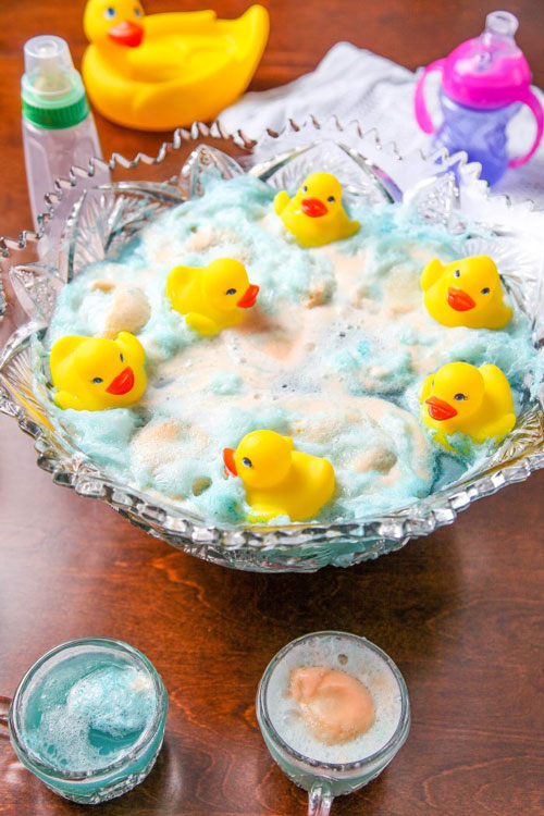 a punch bowl filled with frothy blue punch and floating rubber duckies