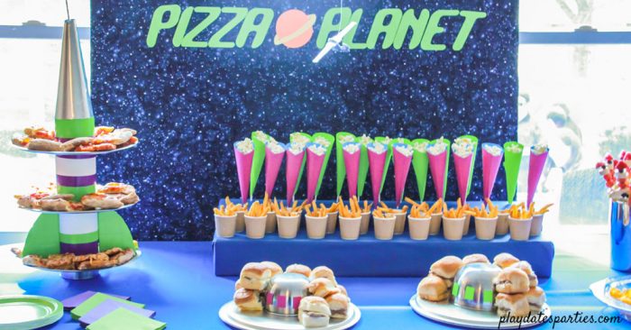 Pizza planet party buffet with rocket ship tray purple and green cones and UFO platters