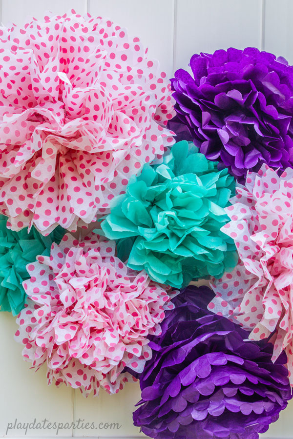 Several brightly colored tissue paper pom poms in a bunch