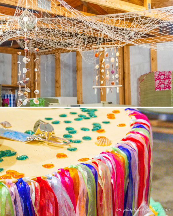 Fishnets and seashell wind chimes hanging from a ceiling, and a table with a ribbon skirt and glass beads scattered on top