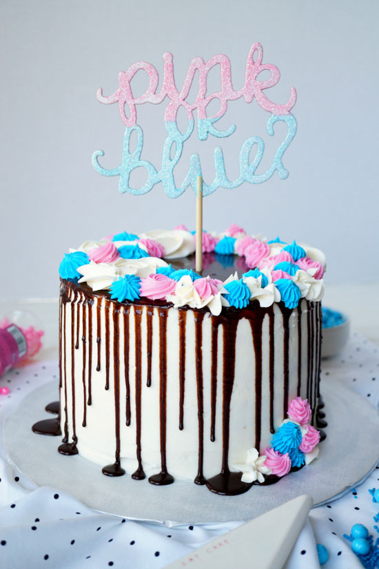 A picture of a beautifully decorated cake with a pink or blue cake topper