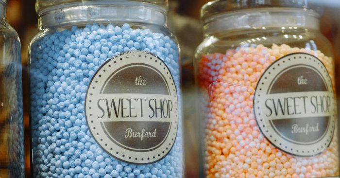 Two glass candy jars next to each other. One with blue candy and one with pink candy.