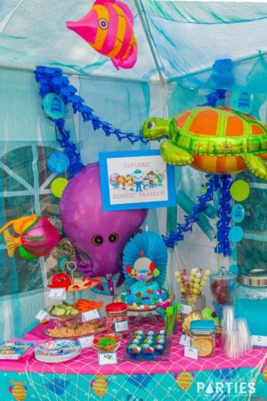 Octonauts party snack table with sea creature balloons, blue streamers, and a party sign