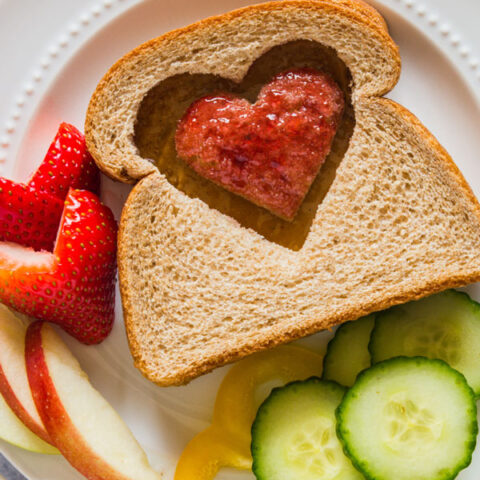 Peanut butter and jelly sandwich with a heart cut out of the top slice of bread.