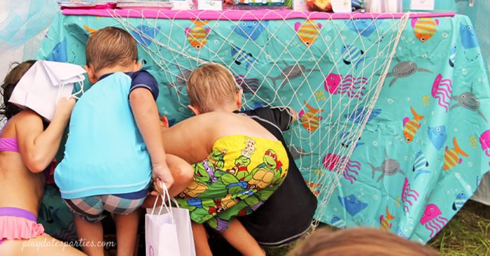 A picture of kids looking under a table at a party for kids treasure hunt ideas.