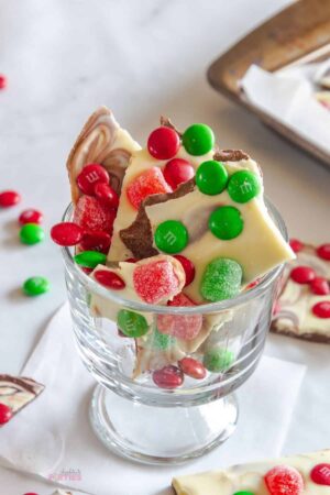 Holiday candy made with chocolate and candy in a footed glass bowl.