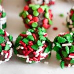 Close up of a row of boozy holiday truffles covered with sprinkles.