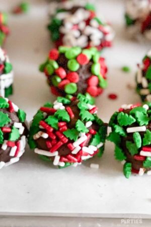 Close up of a row of boozy holiday truffles covered with sprinkles.