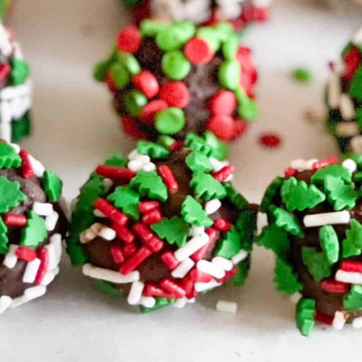 Close up of a row of boozy holiday truffles covered with sprinkles.