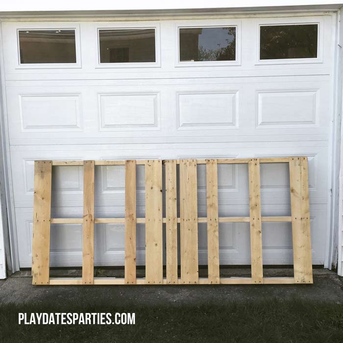 A large unfinished pallet against a garage door.