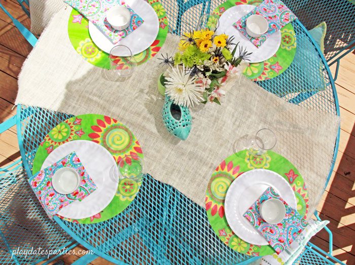 Picture of a bright blue painted patio set with place settings and a white burlap table runner.