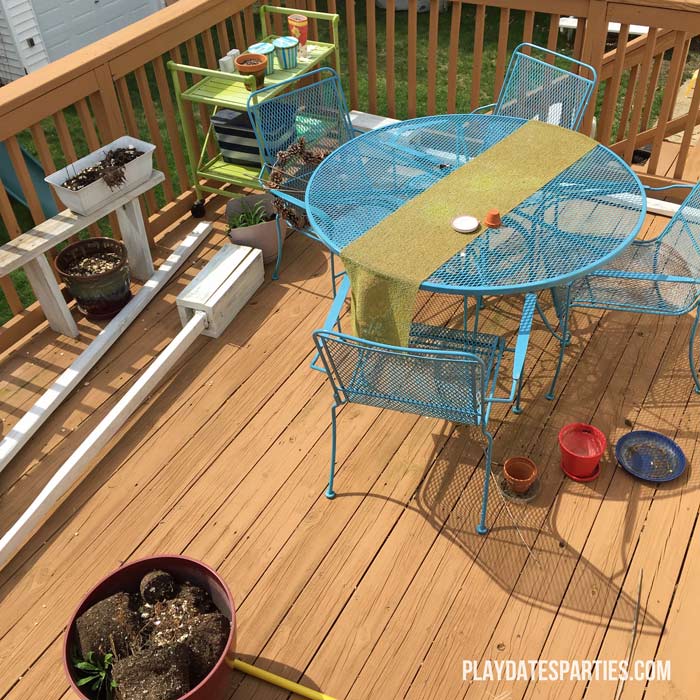 Picture of a deck with a bright blue patio set, green serving cart, and patio boxes.