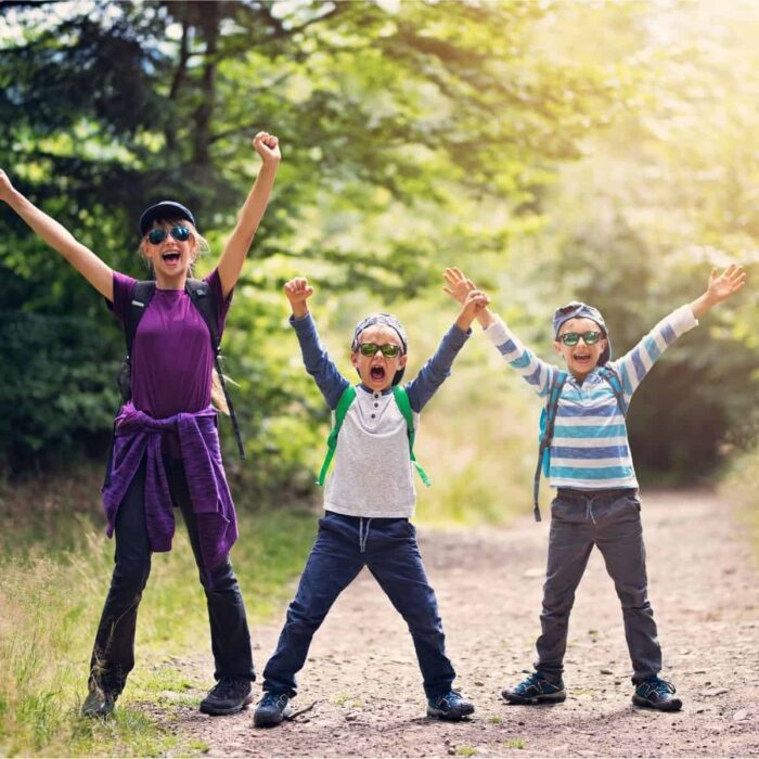 a family hiking in the woods with arms up in excitement