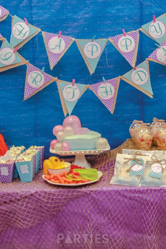 Blue pink and purple birthday party with fish netting and a layered banner