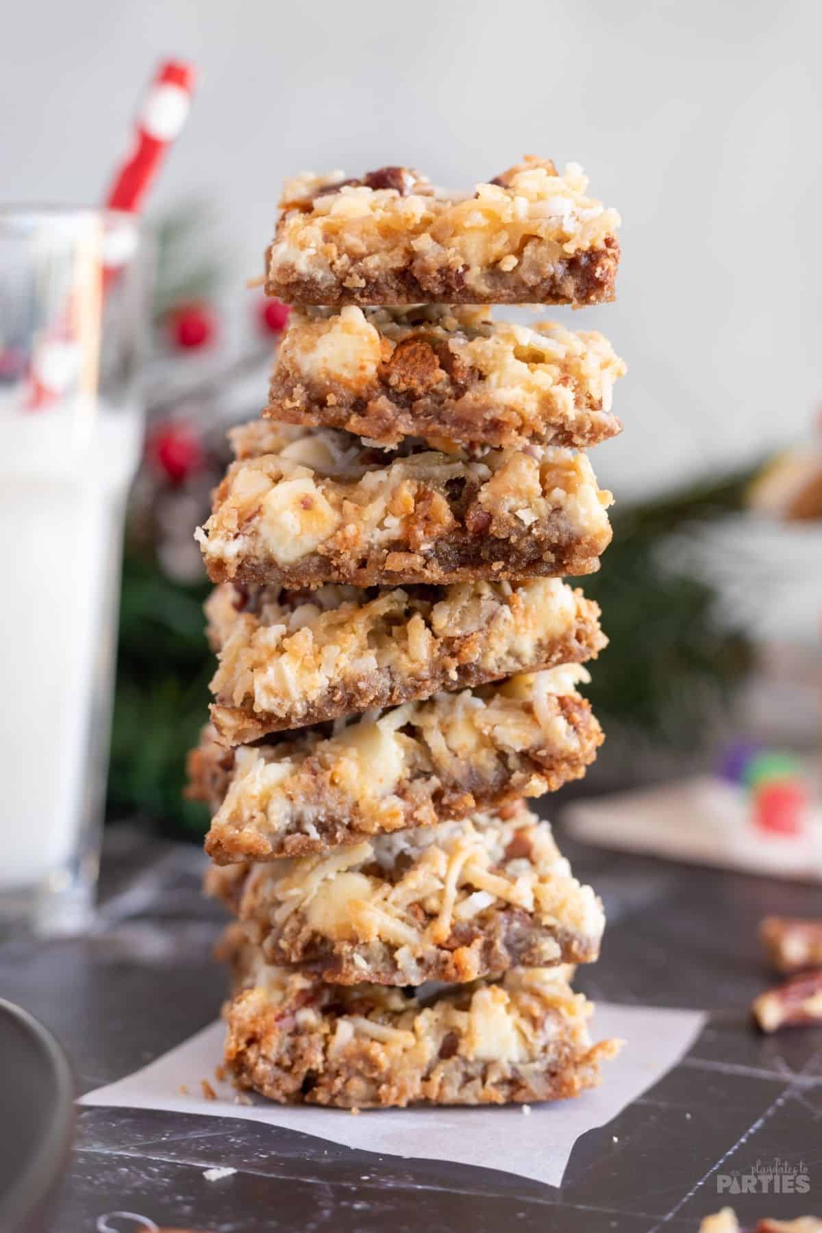 Seven gingerbread magic cookies are stacked on a black marble surface, with holiday decorations in the background.