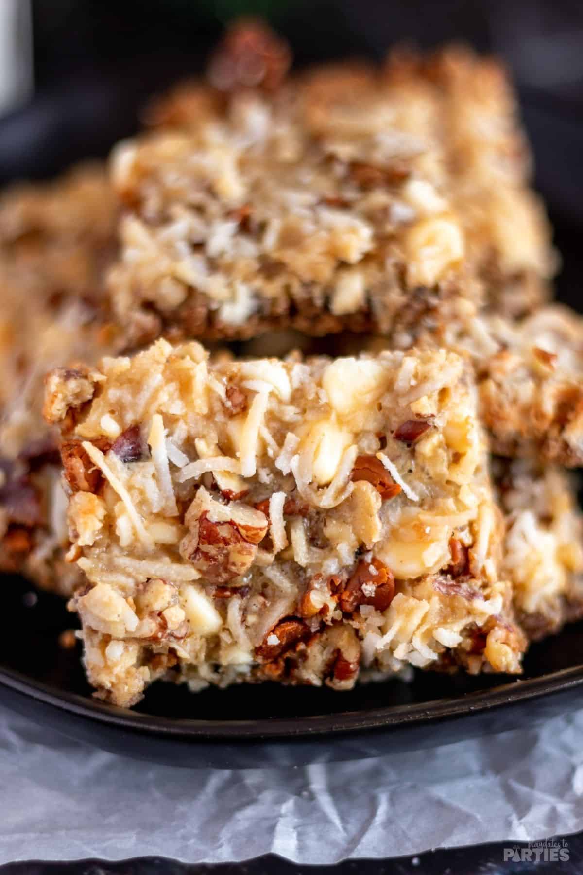 A close in view of dessert bars with pecans, cinnamon chips, coconut flakes, and ginger.
