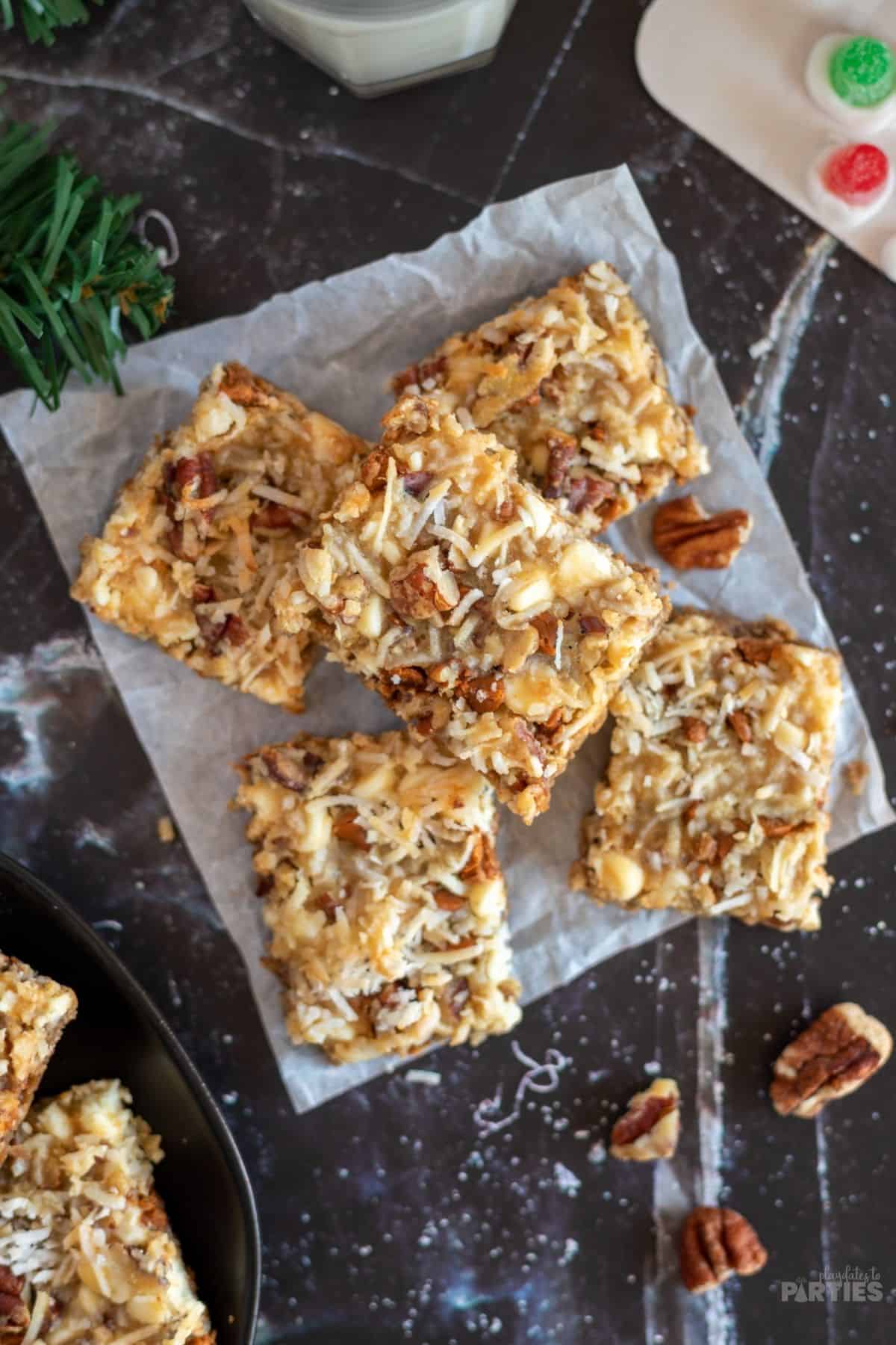 An overhead look at 7 layer magic bars made with pecans on a piece of parchment paper.