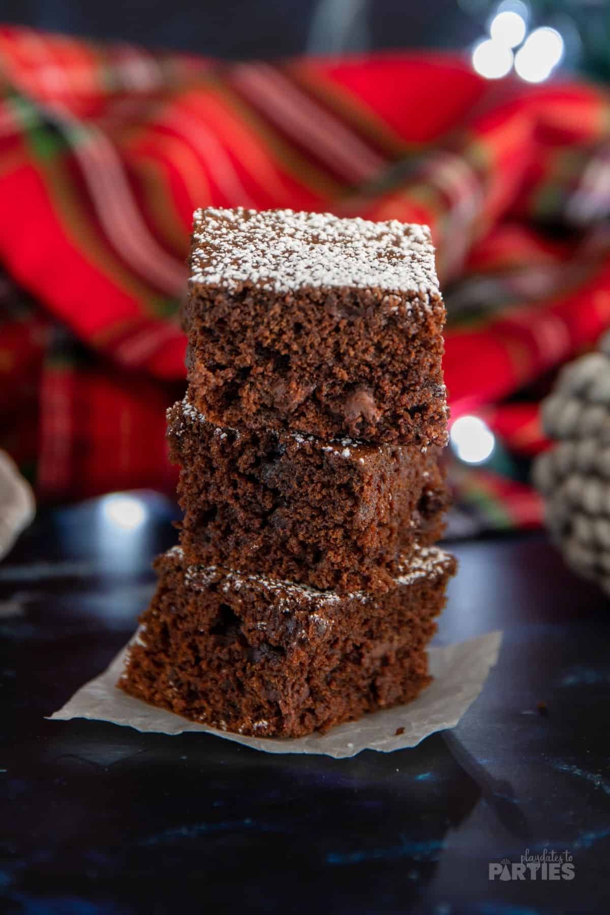 Three dark chocolate gingerbread bars stacked on a dark surface.