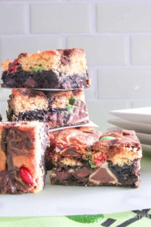 Double decker triple stuffed Christmas brownies combine swirled layers of chocolate brownie and yellow cake stuffed with Hershey's Hugs, Caramel Kisses, and colorful holiday candies.