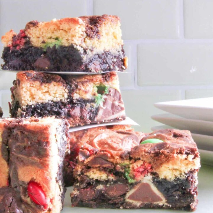 Double decker triple stuffed Christmas brownies combine swirled layers of chocolate brownie and yellow cake stuffed with Hershey's Hugs, Caramel Kisses, and colorful holiday candies.