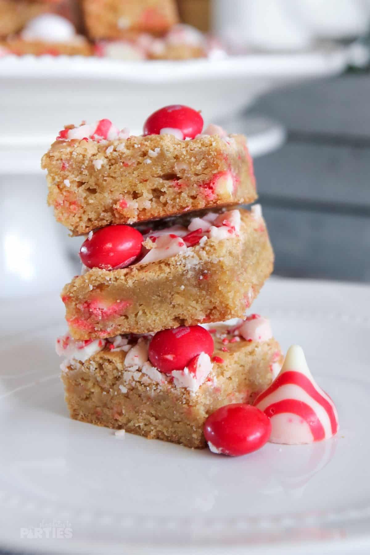 3 Peppermint blondies with white chocolate stacked on a plate.