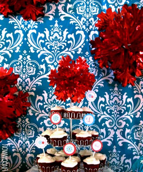 Winter wonderland birthday party with a blue damask backdrop and fluffy red snowflake decorations