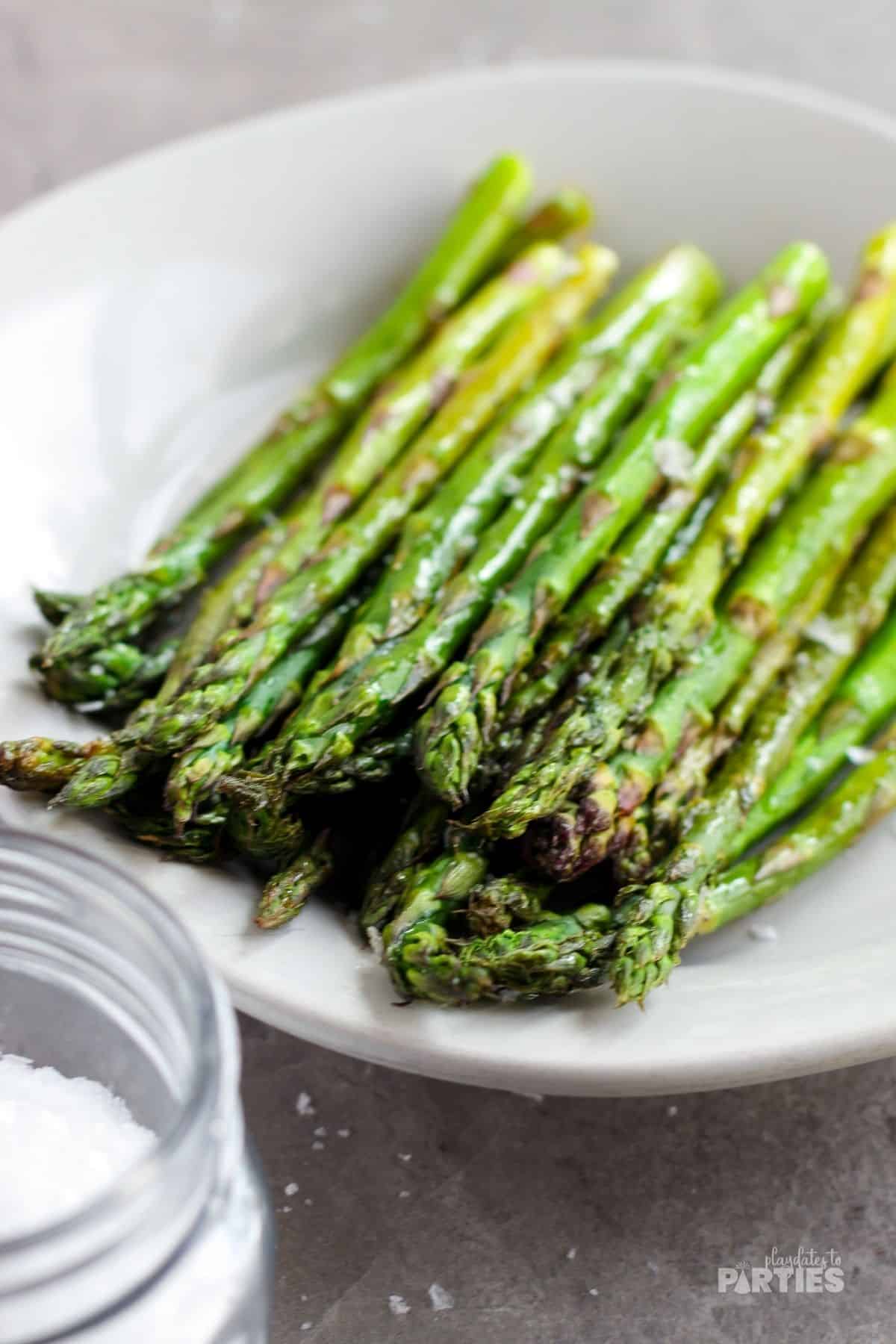 Oven roasted asparagus spears on a white serving platter.