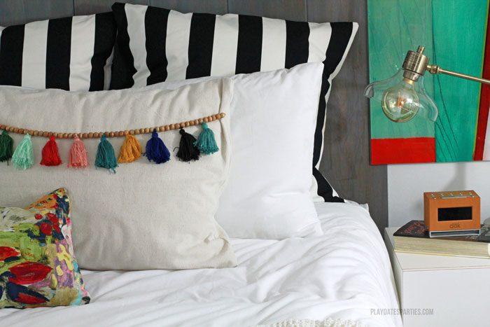 With a neutral textured palette, this modern boho master bedroom shows that you don't need to have a huge bedroom to have function and beauty. Don't forget to check out the customized Ikea storage wall, tassel trim pillows, and bold black striped accents.