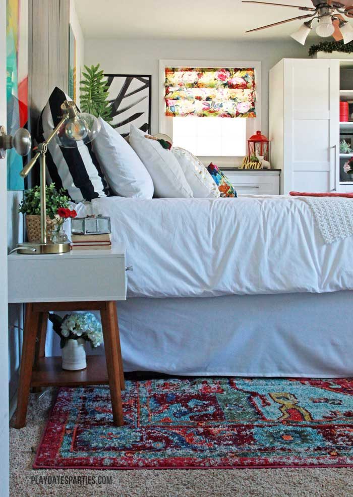 With a neutral textured palette, this modern boho master bedroom shows that you don't need to have a huge bedroom to have function and beauty. Don't forget to check out the customized Ikea storage wall, tassel trim pillows, and bold black striped accents.