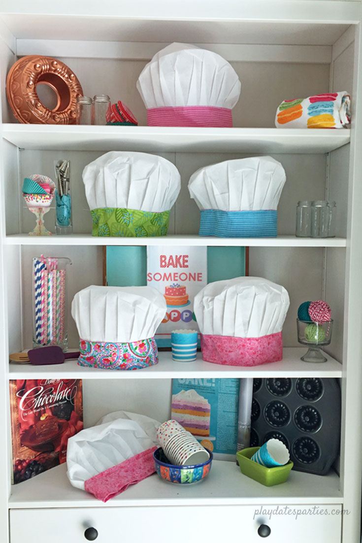 Colorful kids chef hats and baking paraphernalia set up for a birthday party.