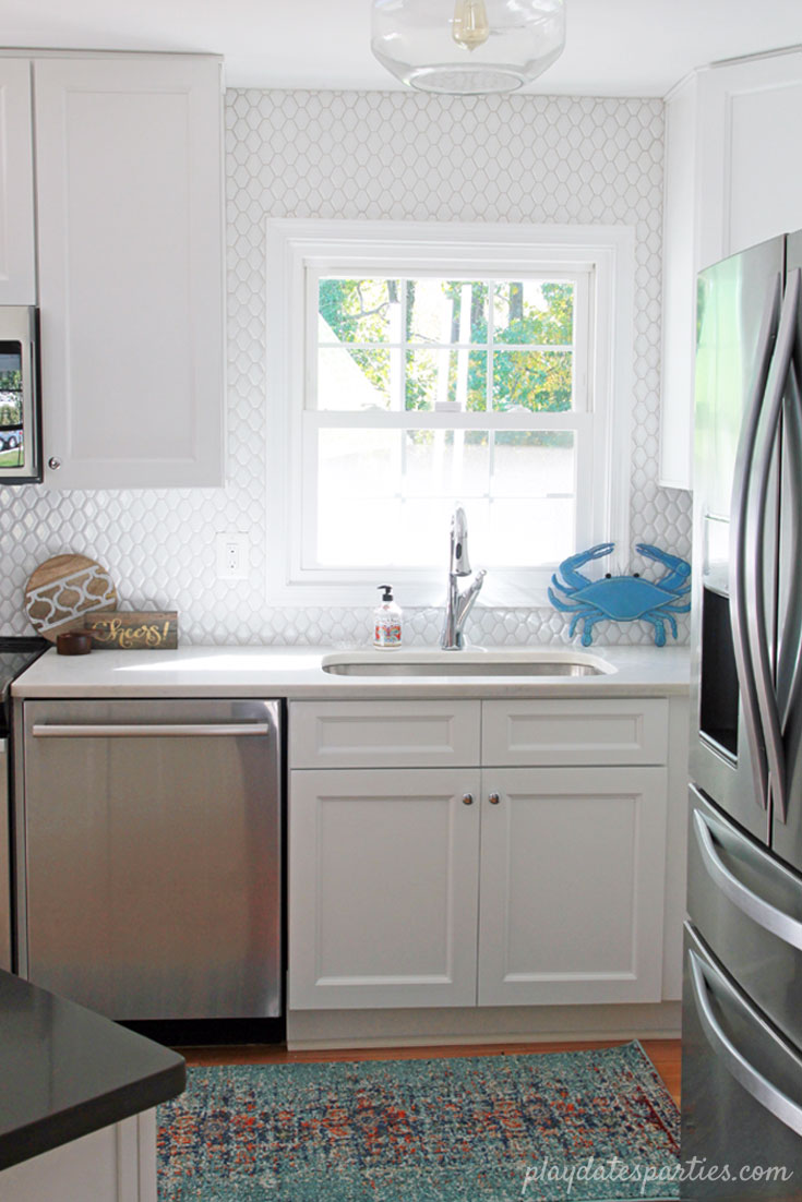 This small white kitchen balances all the white with plenty of texture in the tile backsplash, and pops of color along the countertops.