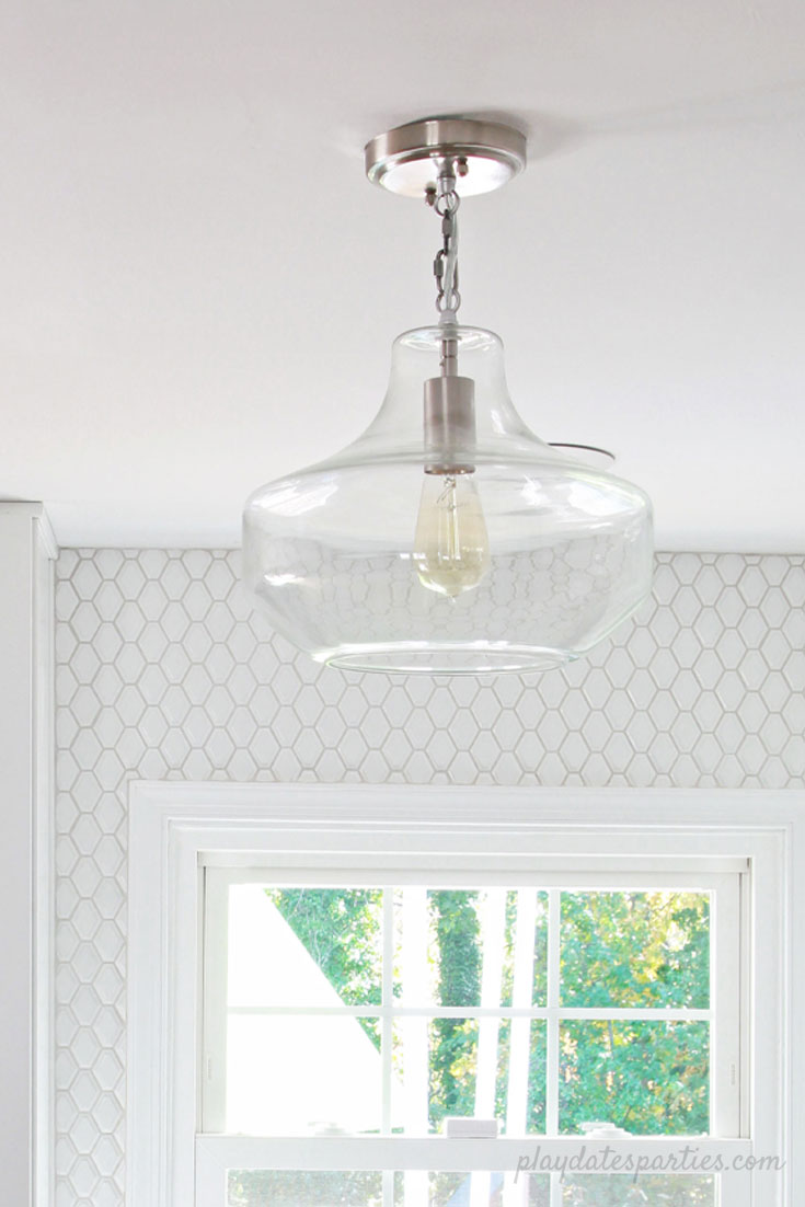 In this bright white kitchen, it's all about adding texture, with beveled tile and a clear glass pendant. Small white kitchen | #Kitchen #renovation #before and #after