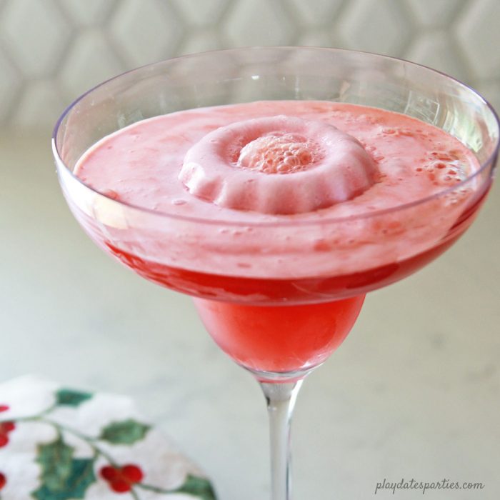 This cherry ginger mock margarita recipe is the perfect Christmas party drink for kids to enjoy. They'll love the bright color, fruity flavor, and sherbet wreath in the center of the drink.