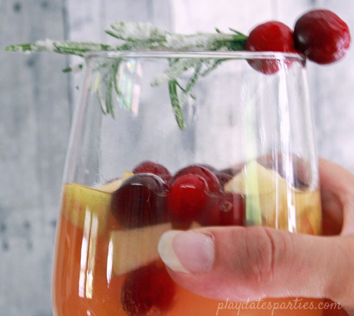 Your holiday brunch needs a pitcher of this white wine holiday sangria with rosemary and cranberries. It's gorgeous right in the pitcher, but the sangria recipe is made even prettier with a garnish of sugar frosted rosemary speared cranberries.