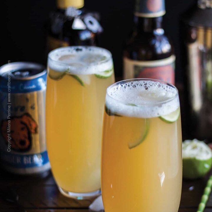 two beer cocktails garnished with lime in front of bottles of IPA