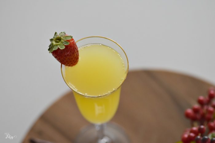 close up of cocktail in a champagne flute garnished with a single strawberry