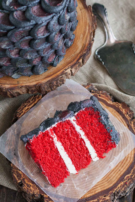 A slice of bright red velvet cake - 3 layers with white frosting between each layer