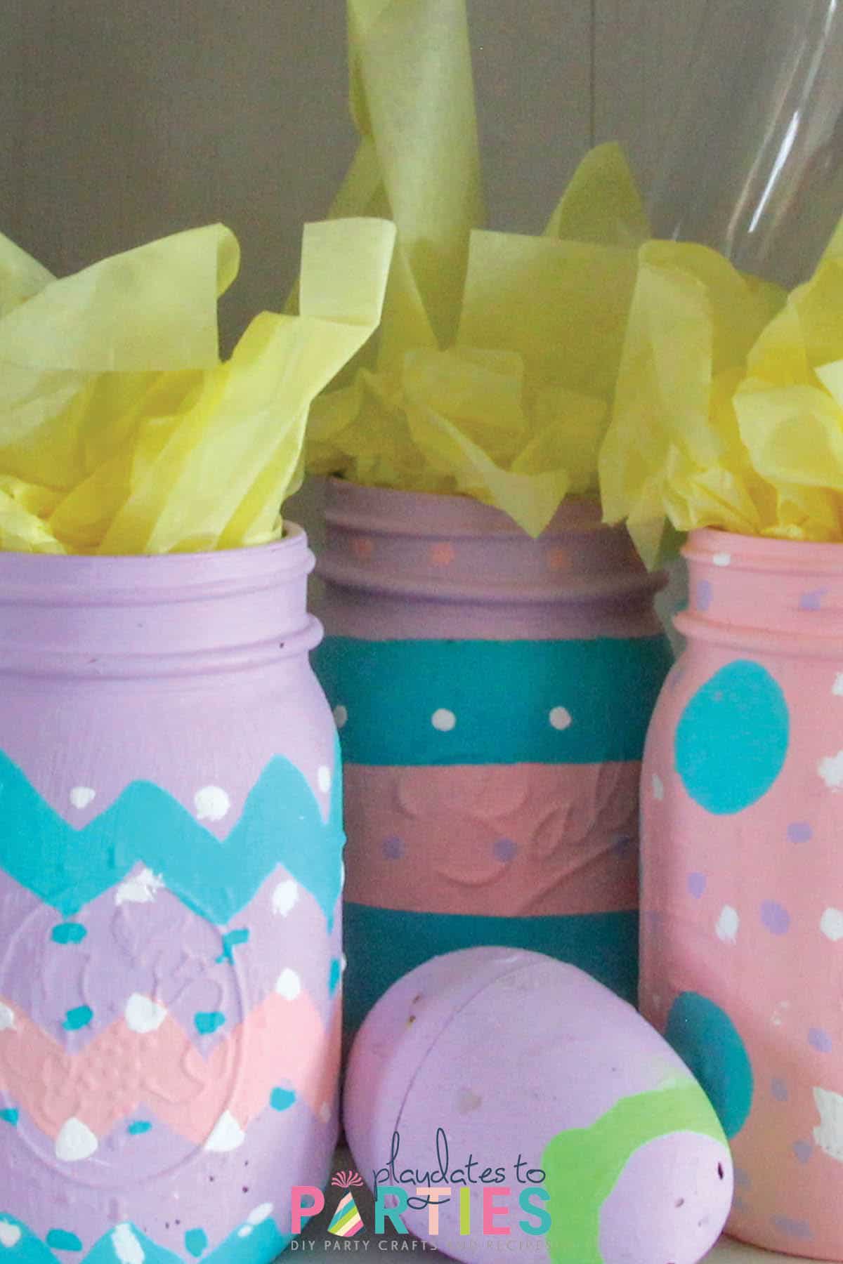 Mason jars painted in spring colors with zig zags polka dots and stripes