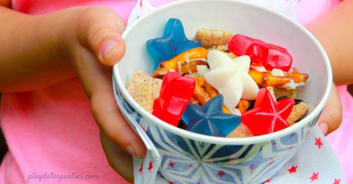 A child holding a bowl of patriotic snack mix