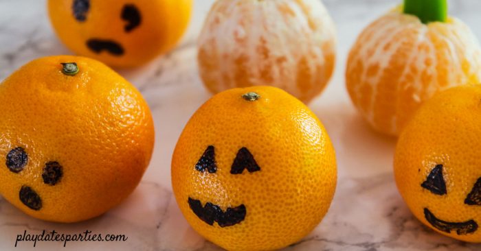 clementine jack o lanterns and peeled clementine pumpkins on a table