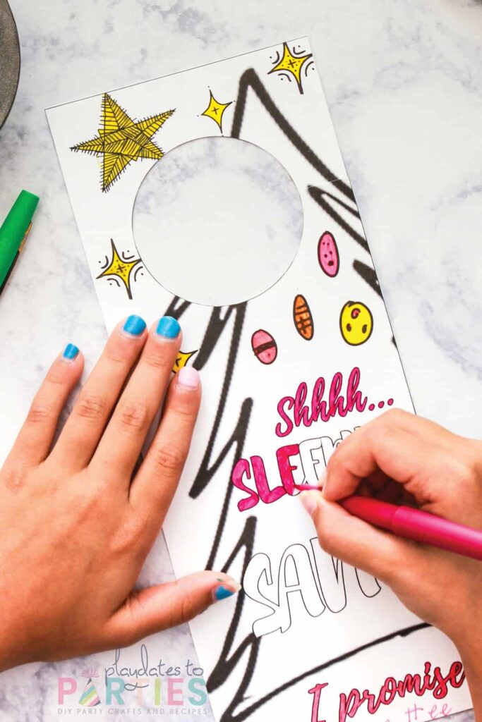 child coloring a door hanger with a picture of a tree and the text shhh sleeping for santa