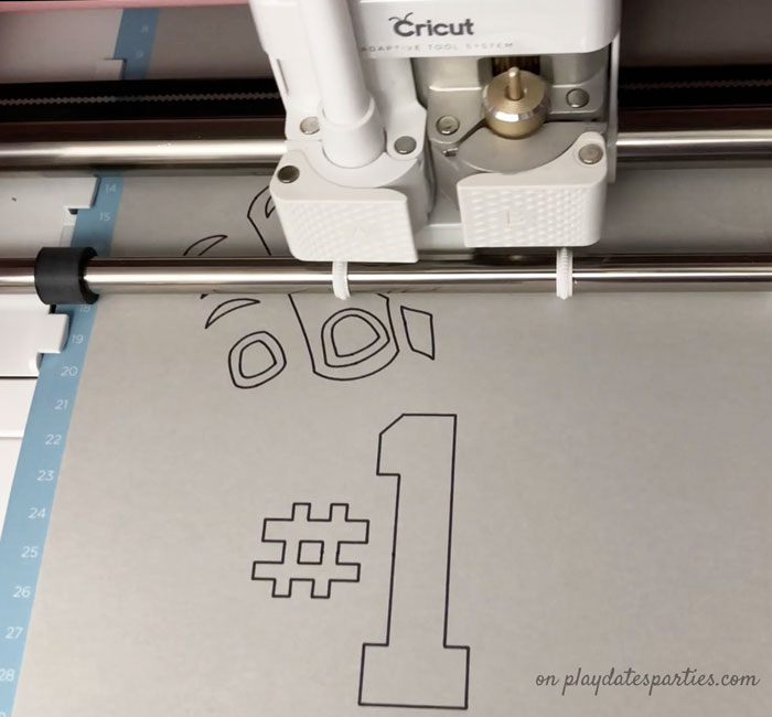 A picture of a Cricut Maker drawing the design for the fan finger football craft