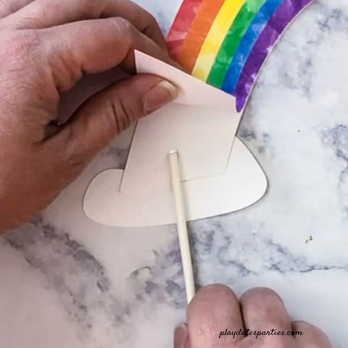 Pot of gold rainbow centerpiece step 4: Glue lollipop sticks to the ends of the rainbow and one side of the cloud.