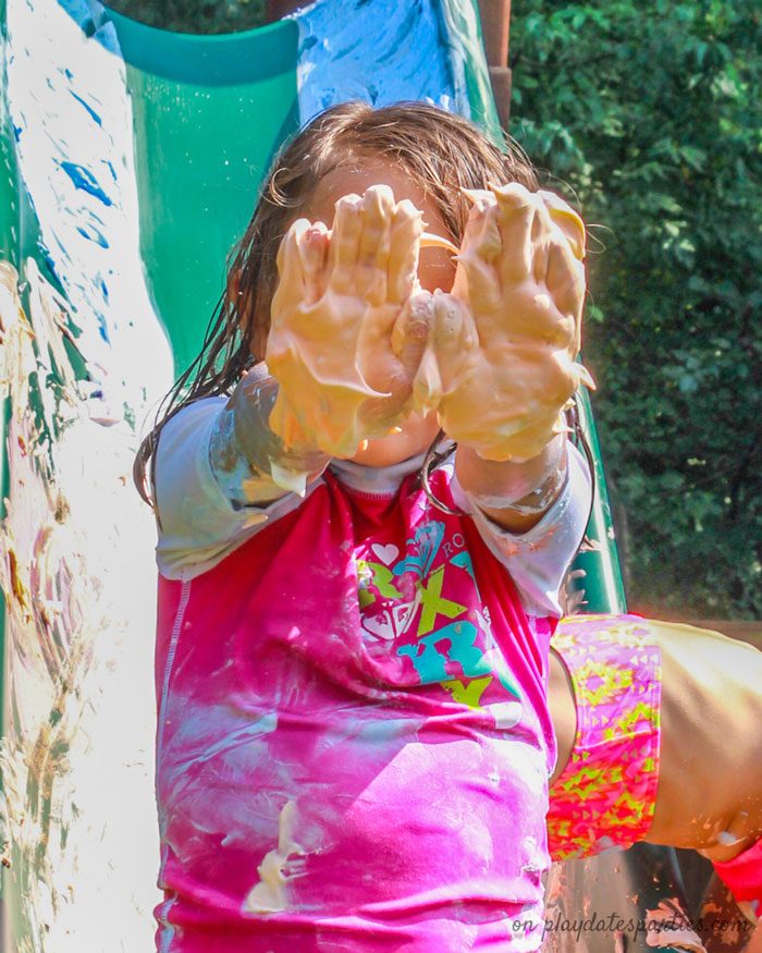 Picture of a child holding up hands covered with orange shaving cream