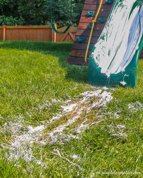 Photo of a slide covered with shaving cream and the shaving cream skid marks in the grass