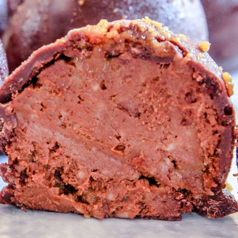 Chocolate pumpkin truffles sitting on a baking sheet.