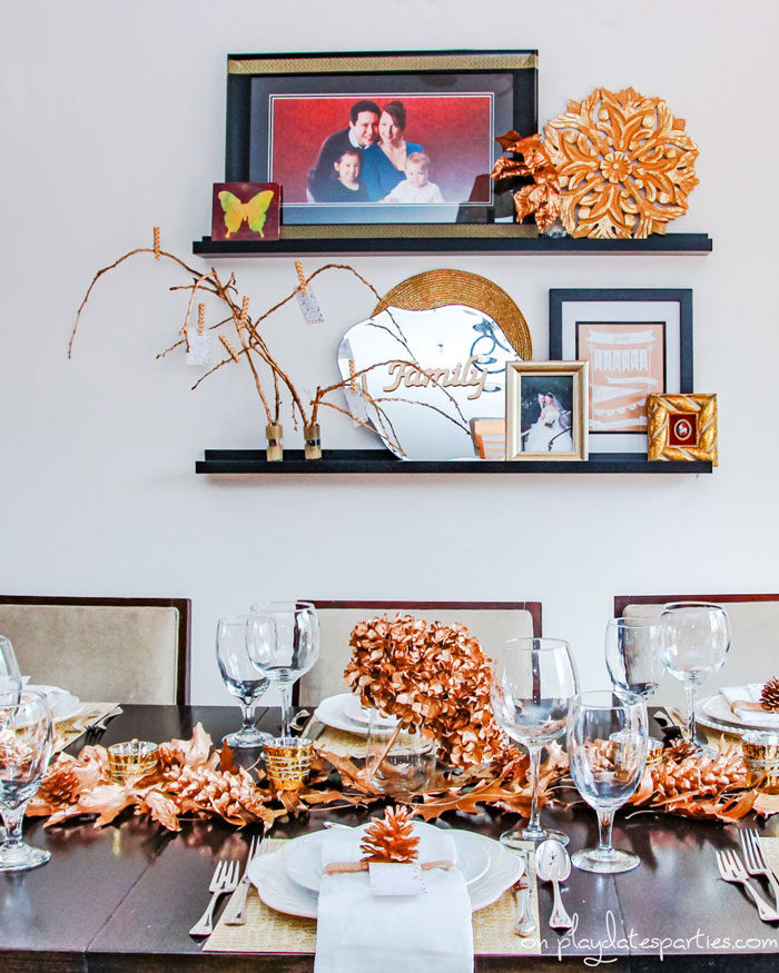 Gold Thanksgiving decor, including gold table decorations, gold branches, and gold sign that says family.