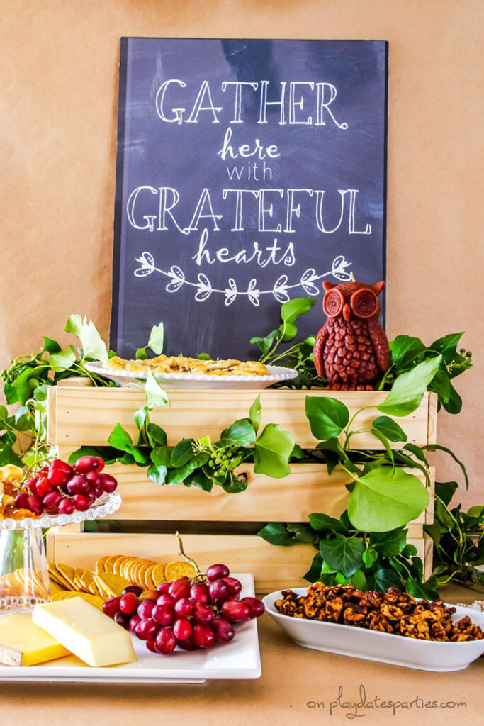 Inexpensive Thanksgiving table decorations on a buffet: a printable sign, a wood crate, an owl candle, and fresh branches from the backyard