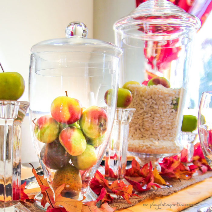 Close up of Thanksgiving centerpieces with hominy and fresh baby apples in apothecary jars